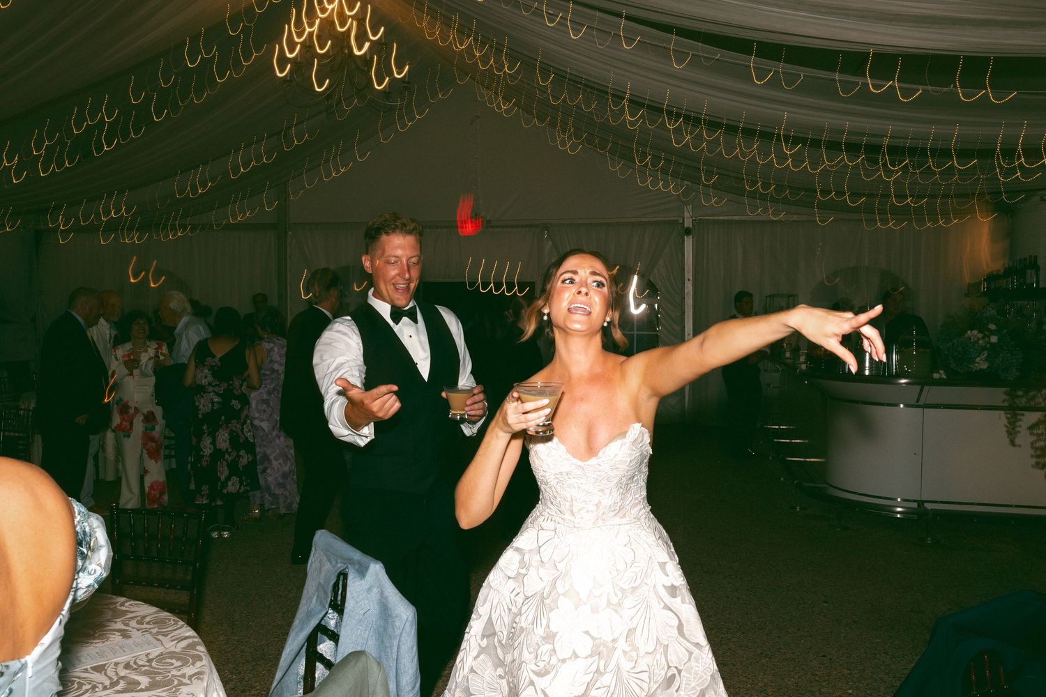 Wedding reception dance party with guests celebrating under decorative lighting.