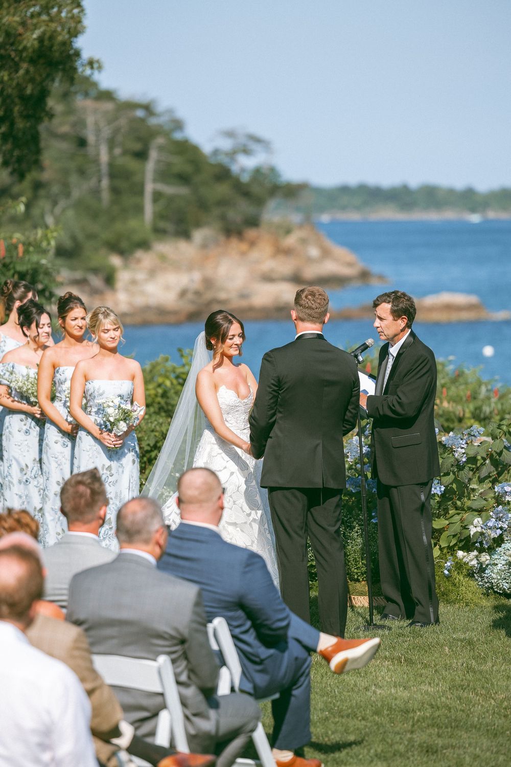 Outdoor wedding ceremony takes place on a scenic coastal bluff overlooking the ocean.