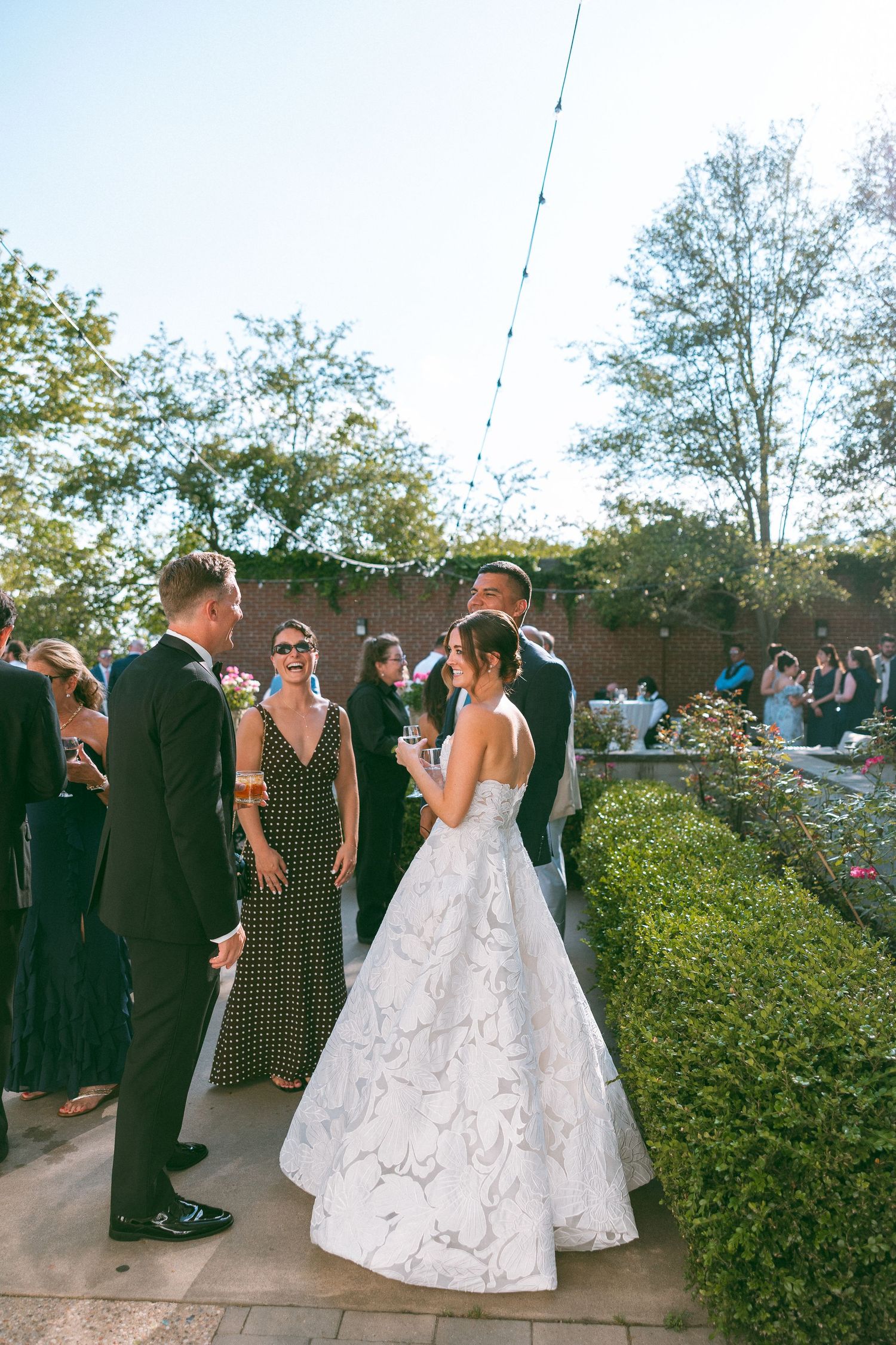 Wedding reception guests mingle outdoors under string lights at dusk.
