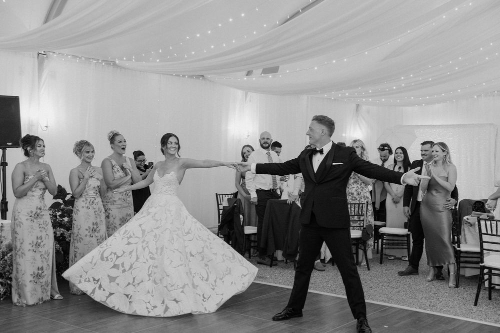 Wedding celebration in a white-draped tent with couples dancing on the floor.