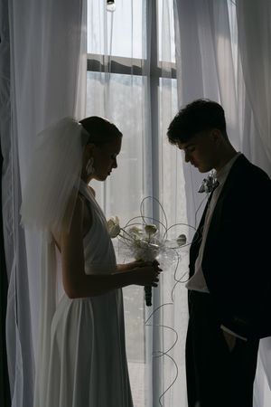 Silhouetted figures stand behind sheer white curtains while using mobile phones and electronic devices.