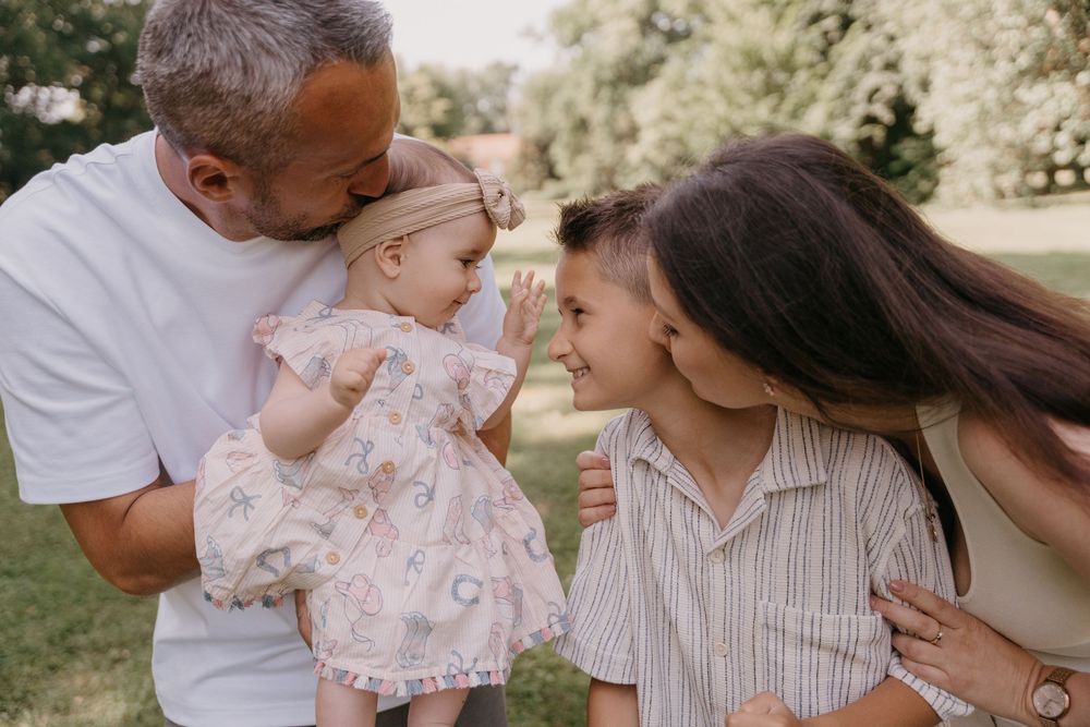 Ein zärtlicher Familienmoment im Freien, bei dem sich alle eng aneinander lehnen.