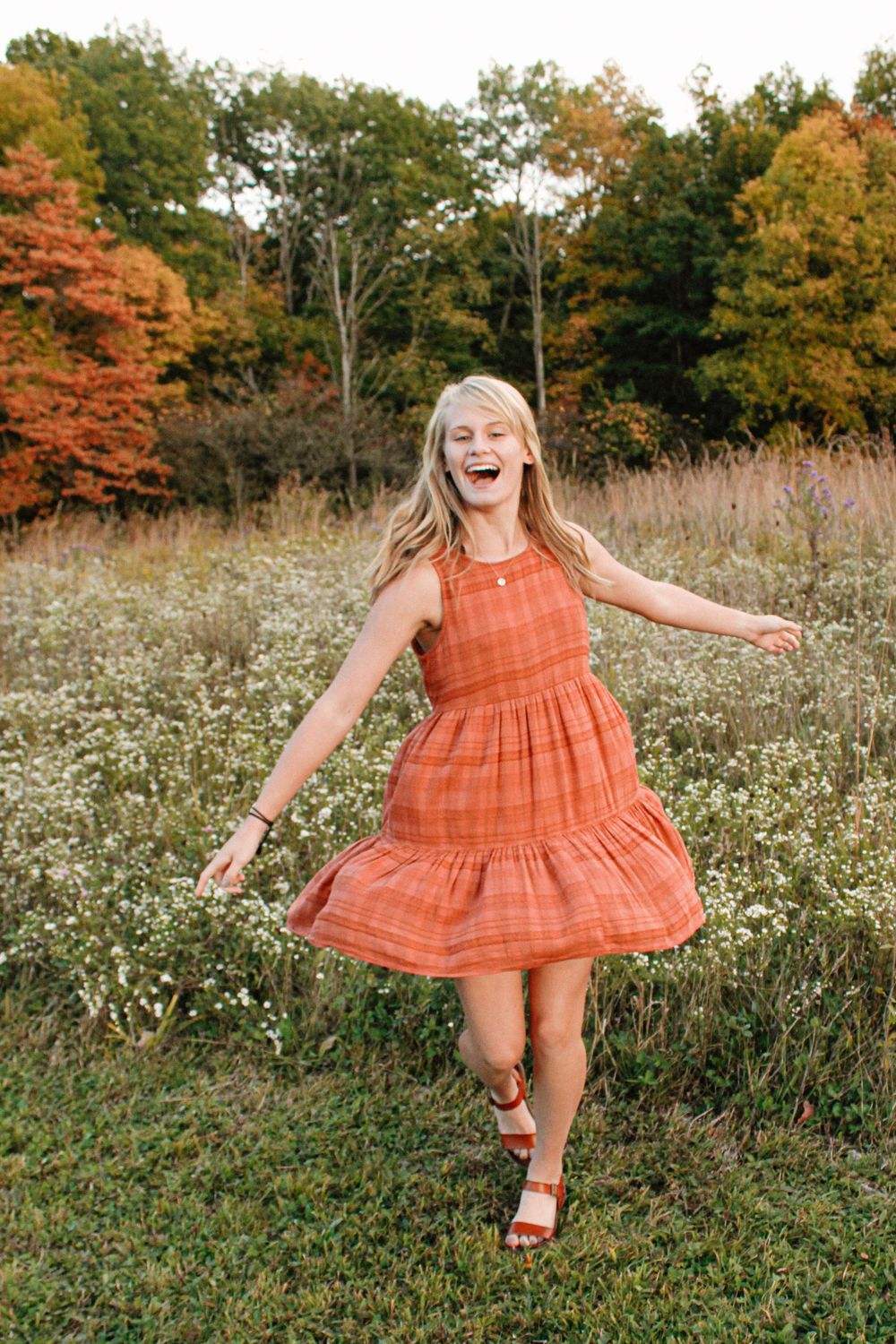 Senior girl spinning in a field of flowers during golden hour.