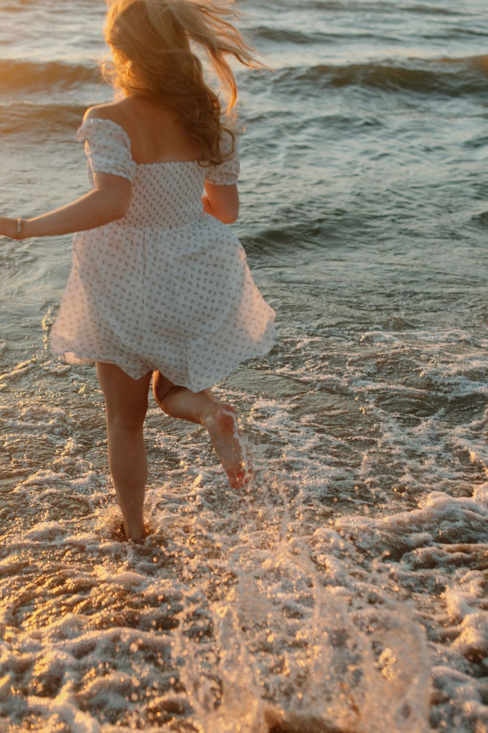 Senior girl at a beach sunset photo session in Holland, MI running into Lake Michigan.