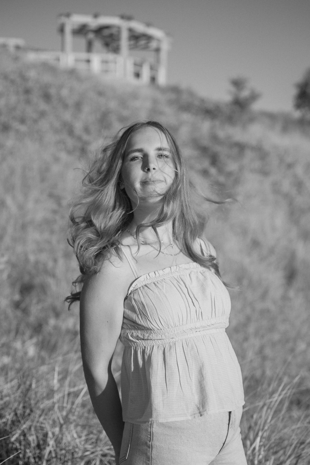 Senior girl flipping her hair at a beach sunset photo session in Holland, MI in black and white.