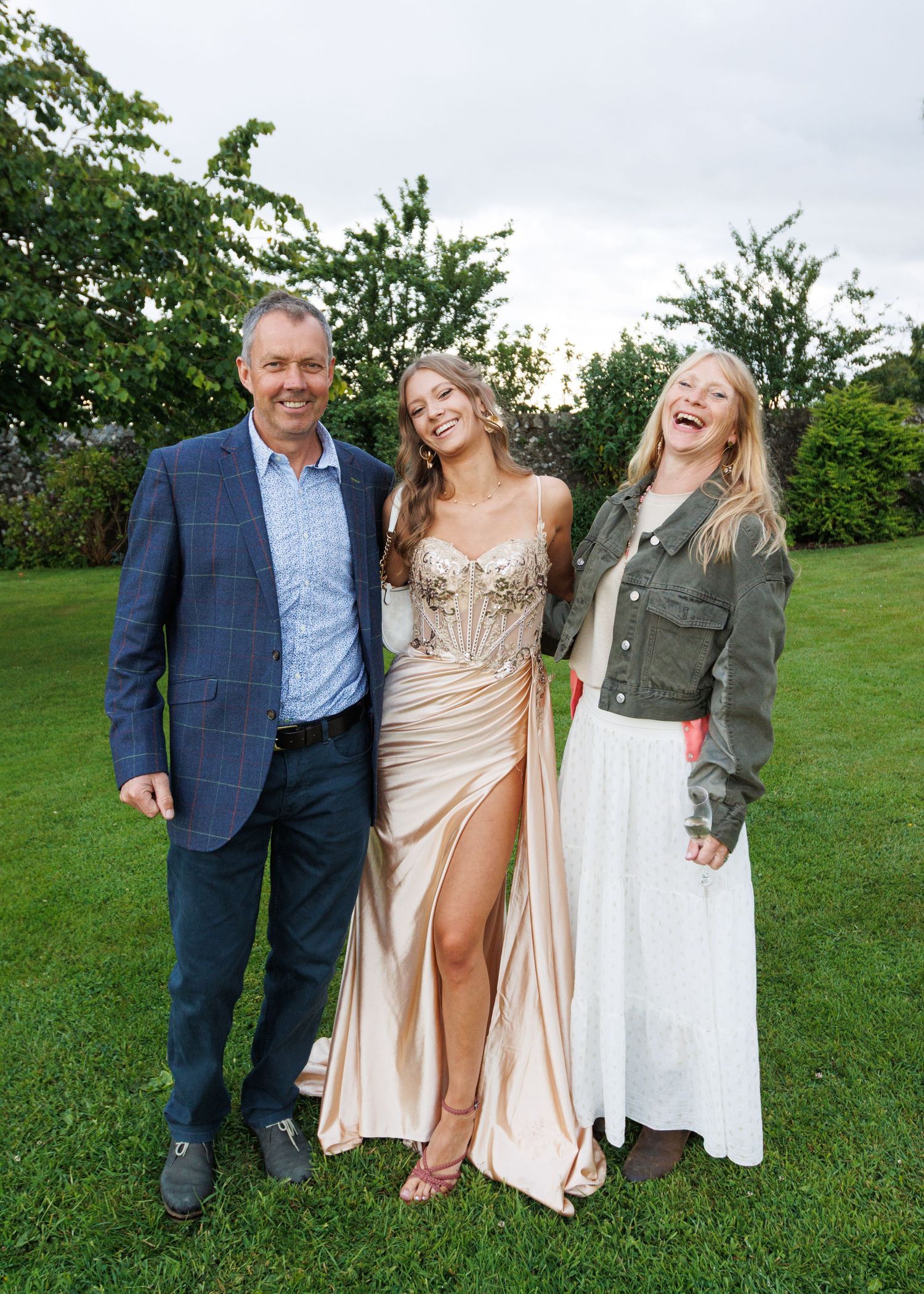 People posing together outdoors on green grass during a formal event.