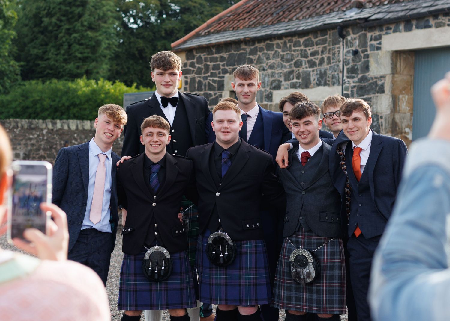 A group in traditional Scottish kilts pose together for a festive photo at a wedding.