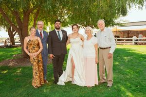 Wedding party portrait outdoors with formal attire standing together under willow trees.