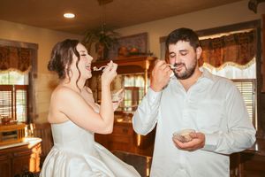 Wedding couple shares a romantic first dance in a warmly lit rustic indoor venue.