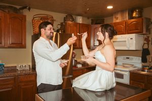 Two people having an energetic moment while cooking together in a cozy residential kitchen.