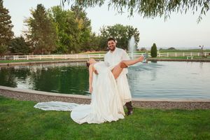 A playful wedding photo by a pond with the couple enjoying a candid moment on their special day.