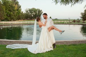 Newlyweds share tender moments by a waterfront setting during their outdoor wedding photoshoot.