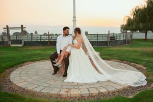 A romantic sunset wedding photo on a circular stone patio with willow trees in the background.