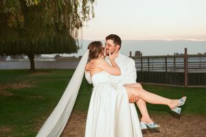 A romantic wedding photo session captures tender moments between a couple near a lake at dusk.