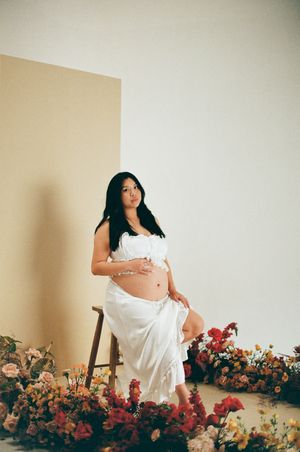 A maternity photoshoot series featuring a figure in white against a backdrop of colorful blooming flowers.