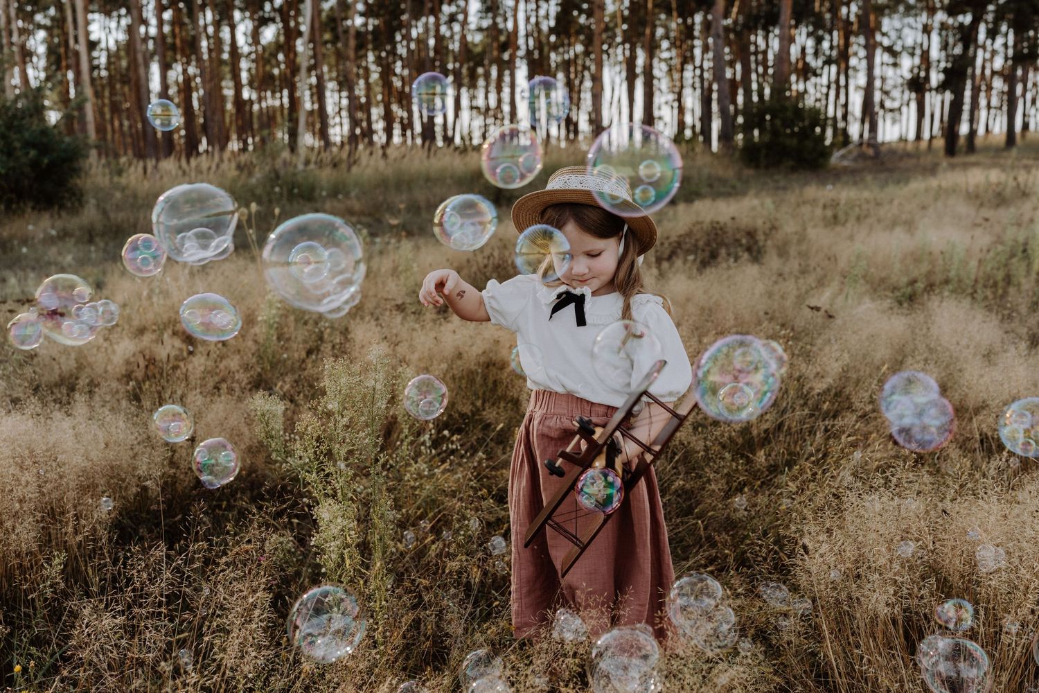 Soap bubbles float through the air in a dreamy autumn field scene.