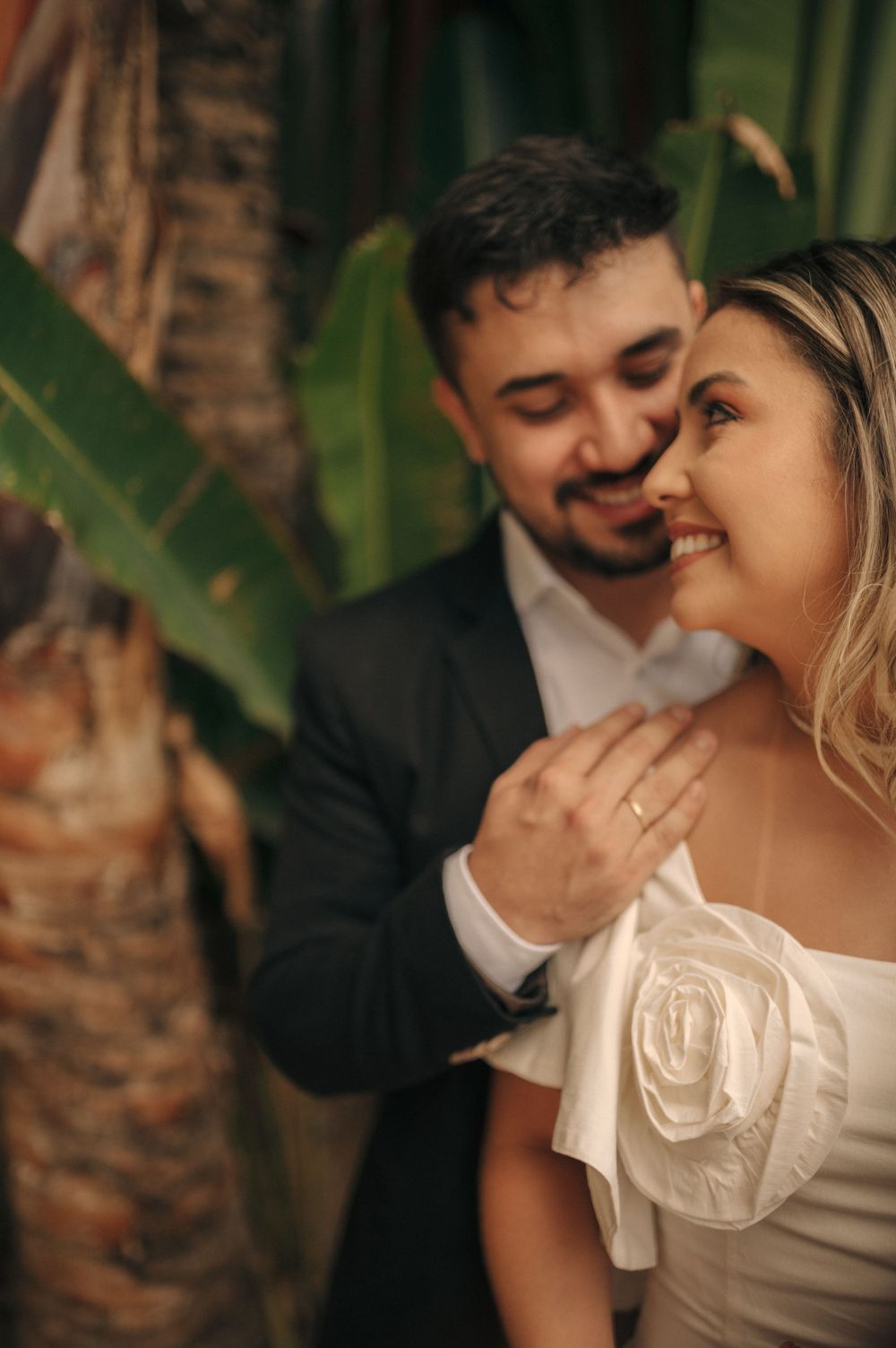 Intimate moment captured between couple among tropical foliage.