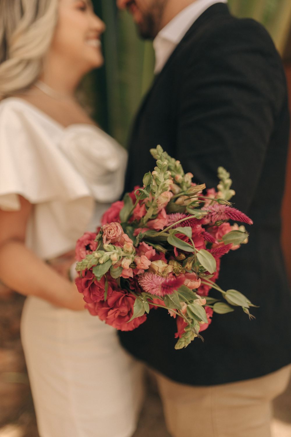 Beautiful pink and green bouquet held against formal wedding attire.