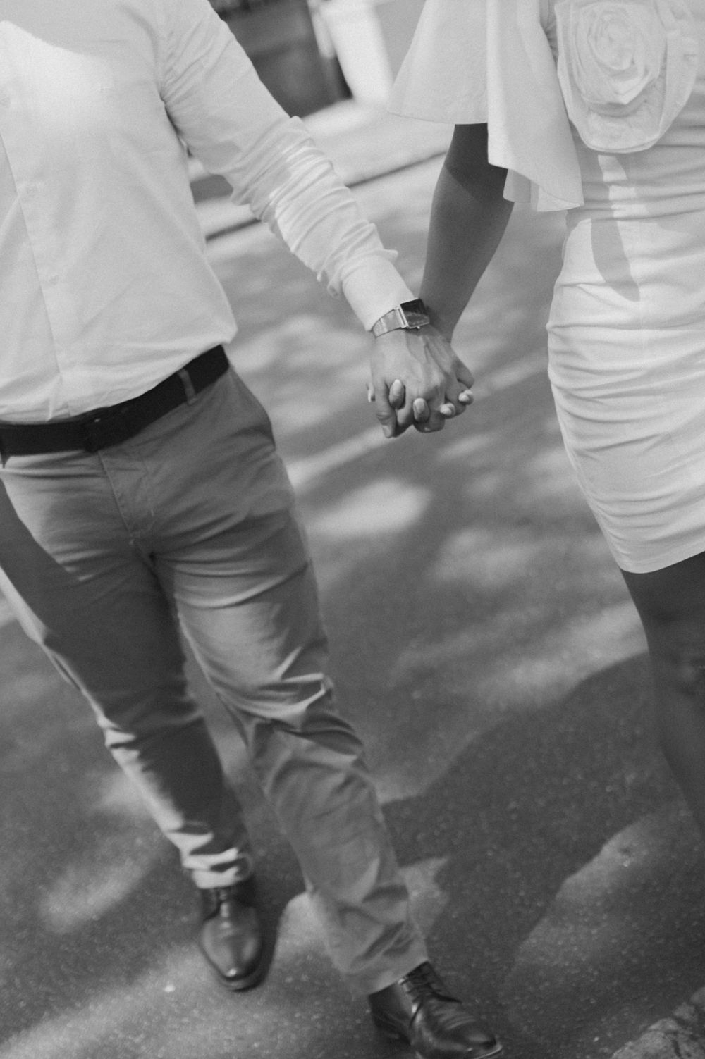 Black and white photo of couple holding hands while walking.