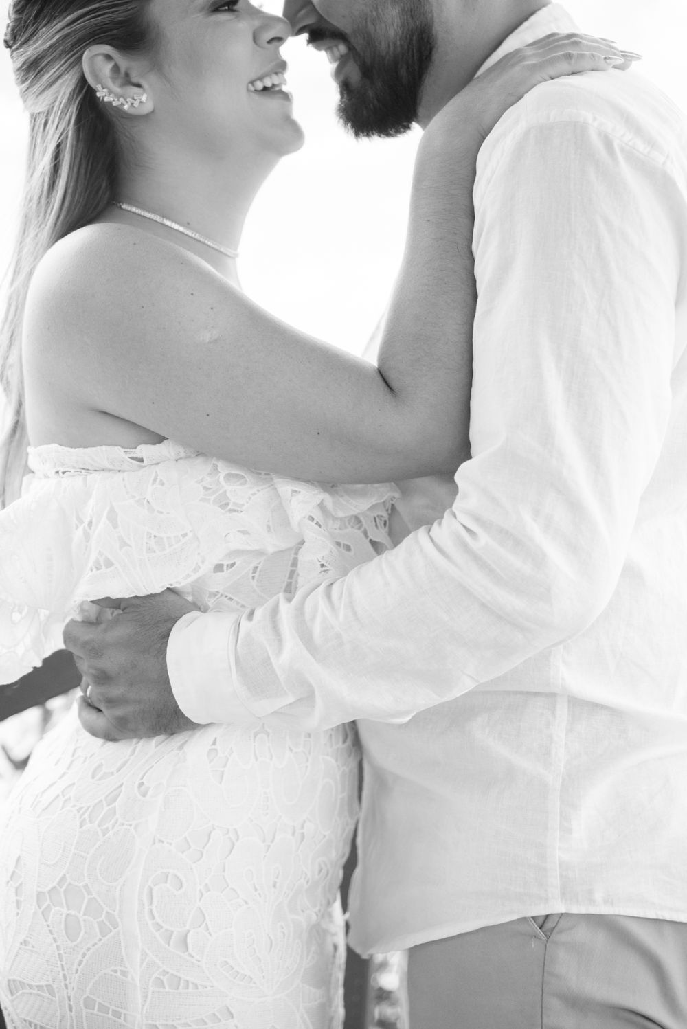 Romantic black and white close-up of a couple in wedding attire embracing.