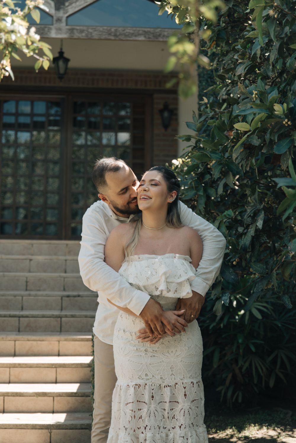 Couple sharing a tender moment on stone steps with ivy-covered walls.
