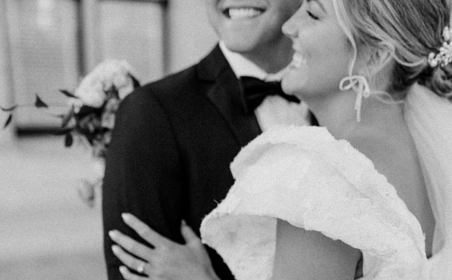 A wedding party shares joyful laughter during formal photos in black and white.