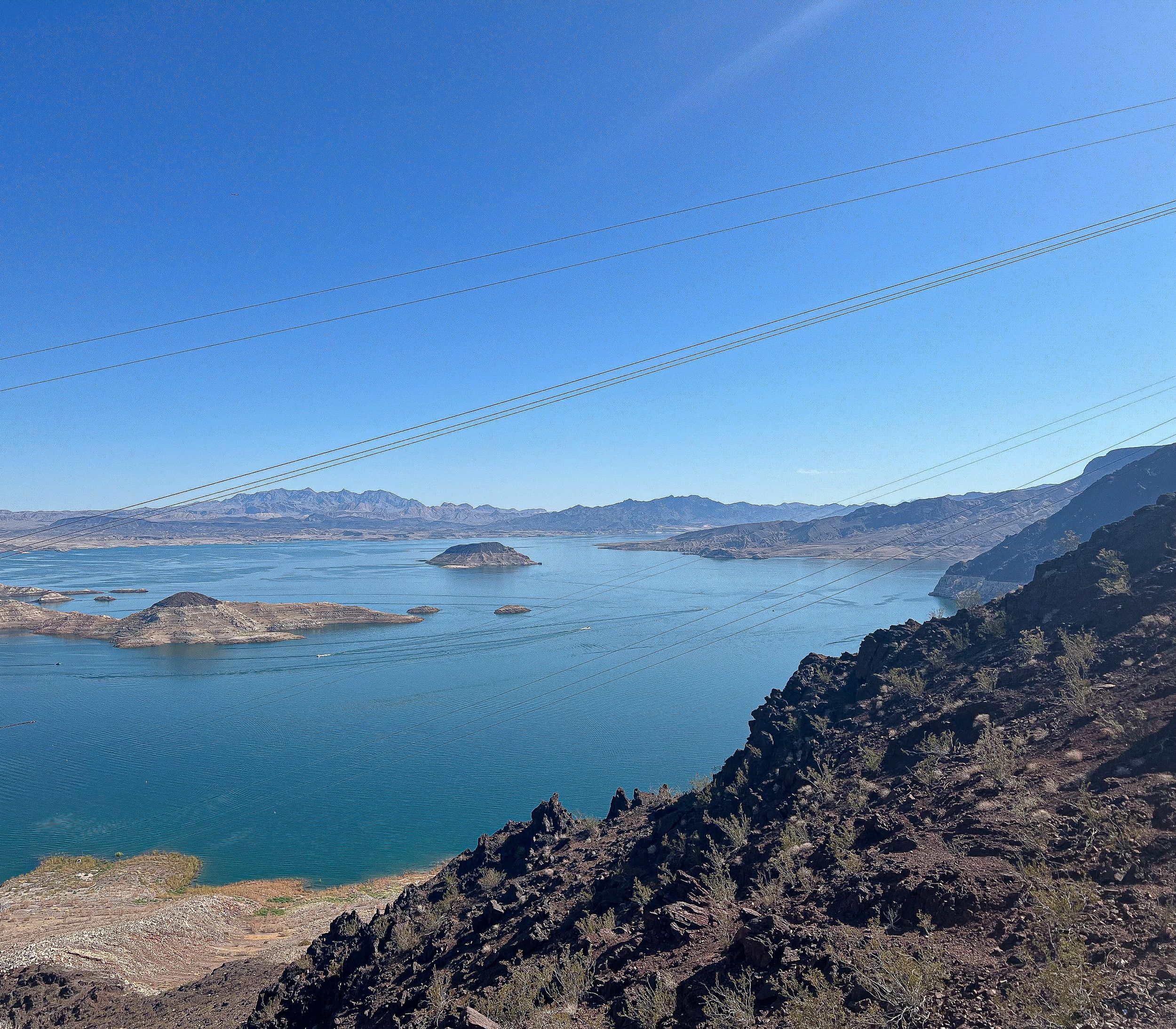 Scenic view of Lake Mead with mountains and islands visible under blue sky.
