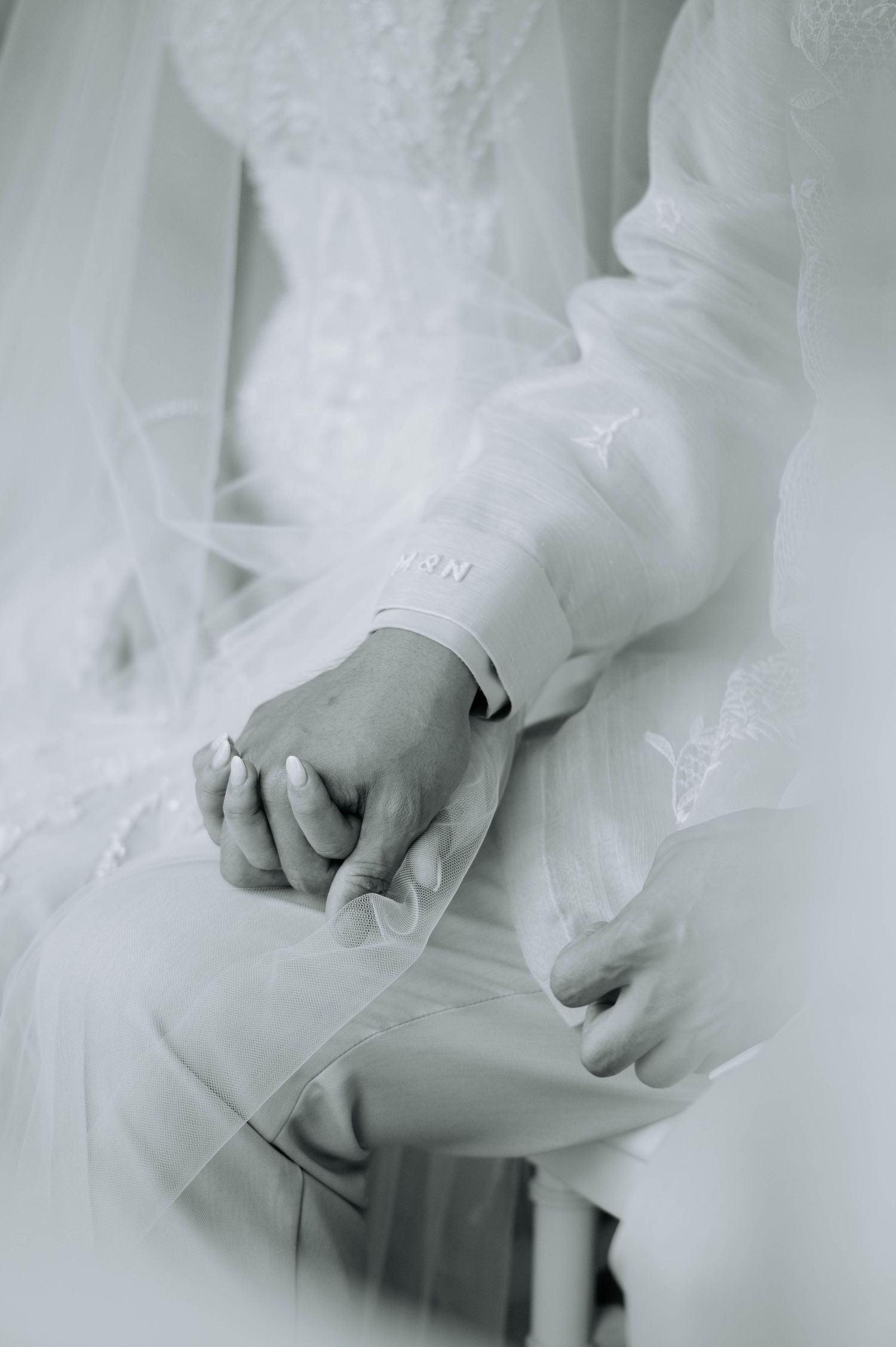 A tender moment showing clasped hands during a wedding ceremony in black and white.