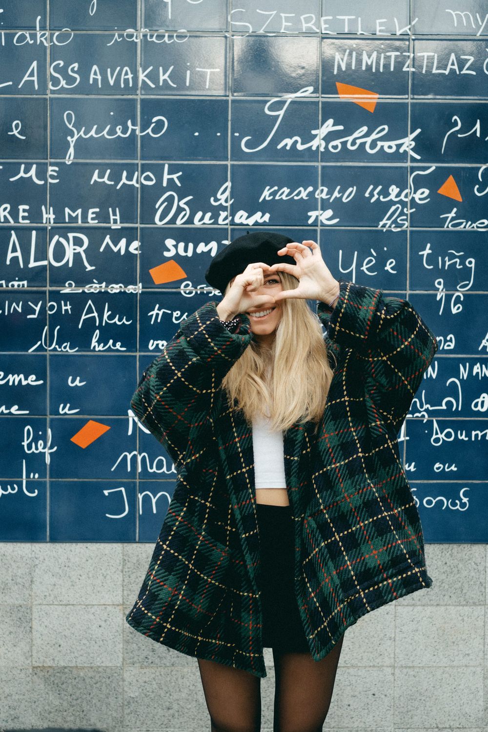 French girl with a barret is making love sign in Monmartre's wall of Love in Paris.