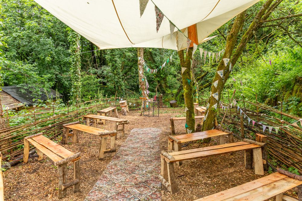 A woodland glade set up with seating and shelter ready for an outdoor pagan wedding.
