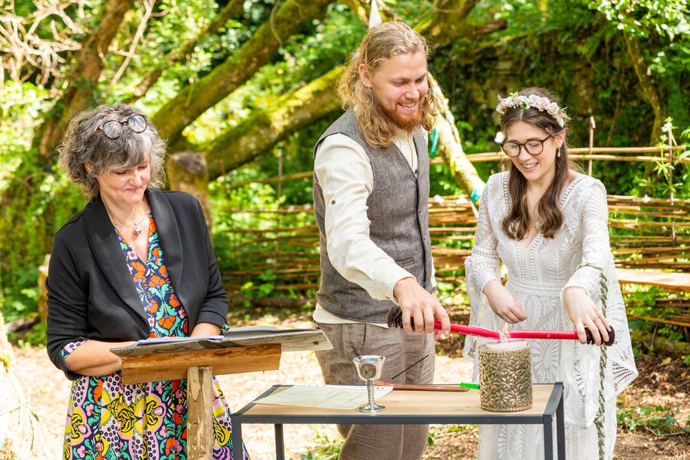A couple lighting a candle during their outdoor Handfasting.