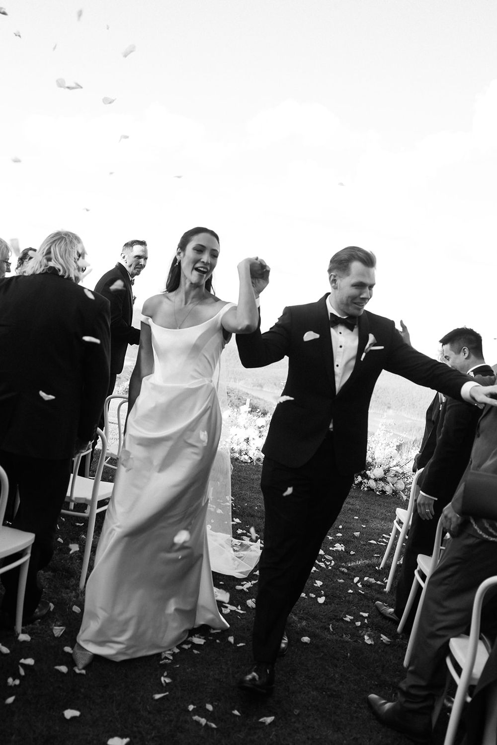 A joyful couple in wedding attire celebrating as they walk down the aisle after their ceremony.