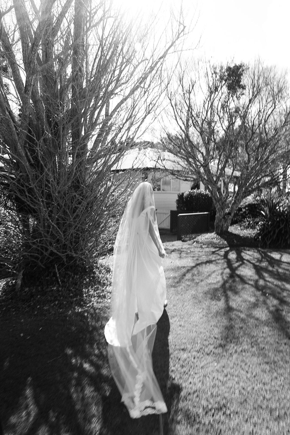 Black and white series showing a figure in white clothing moving across a lawn with shadows and trees.