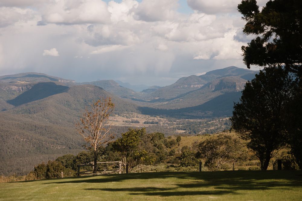 Scenic mountain landscape with rolling hills and meadows under dramatic cloudy skies.