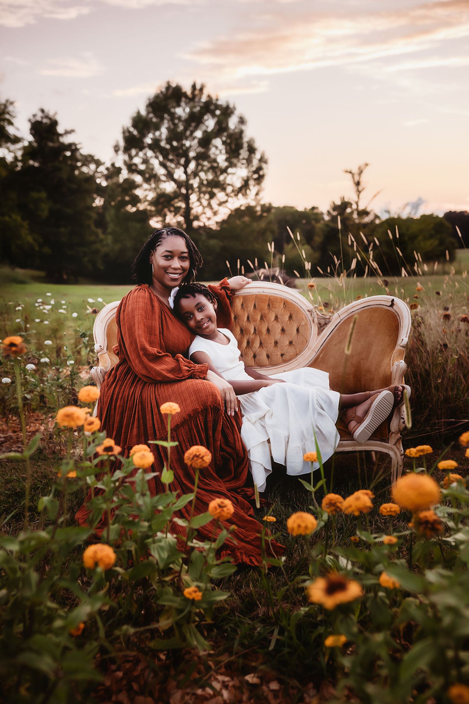 A vintage chair sits in a pumpkin patch with a rustic white barn and autumn foliage in the background.