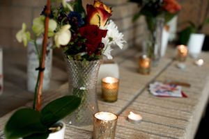 Cut flowers in a crystal vase with glowing candles on a rustic table setting.