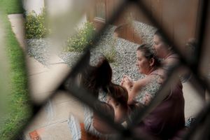 Through window view of people sitting outdoors in garden setting.