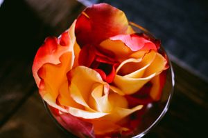 Closeup of orange and red rose petals arranged in a glass container.