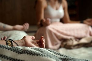 Close-up of hands in meditation pose with a butterfly resting nearby.