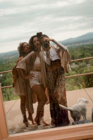 Friends taking photos together on a scenic outdoor deck with mountains in the background.
