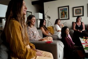 A casual indoor gathering with participants seated on couches wearing comfortable clothing.