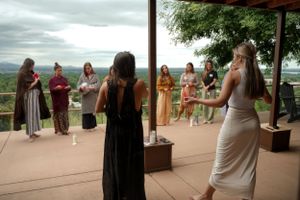 A group gathering on an outdoor deck or patio with mountain views in the background.