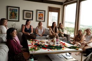 A living room gathering with food and drinks spread on a coffee table surrounded by comfortable seating.