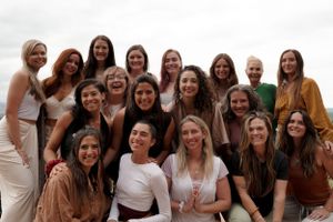 Large group photo of friends gathered together outdoors wearing coordinated neutral-toned outfits.