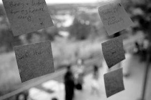 Blurred sticky notes posted on a window with an out-of-focus outdoor scene visible.