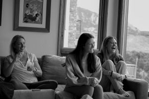 A black and white image of friends sharing laughter while relaxing on a couch.