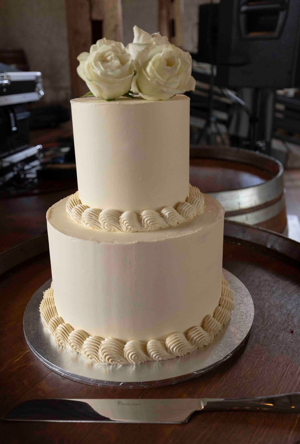 Bride and groom cutting wedding cake in rustic barn reception space