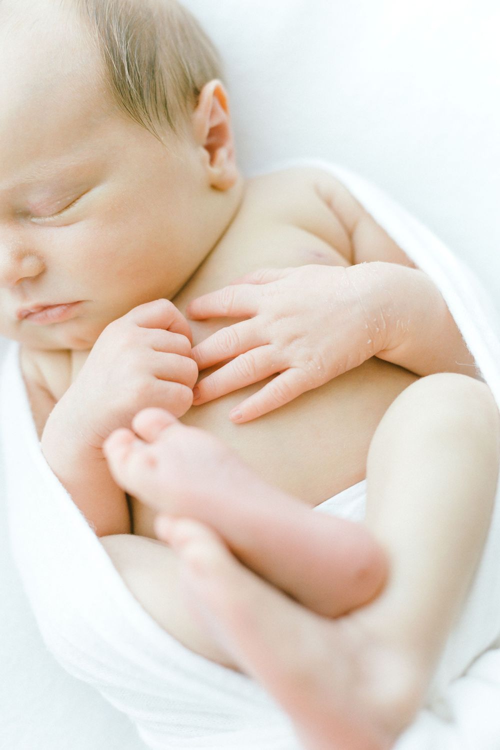 Close-up of peaceful newborn baby resting on white blanket.