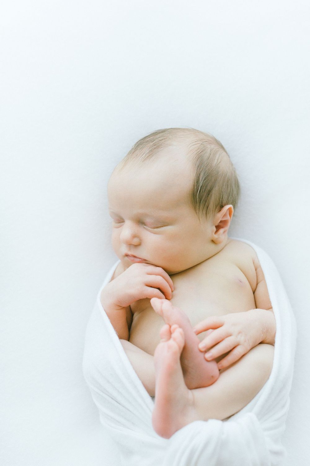 Serene newborn baby sleeping peacefully against white background.