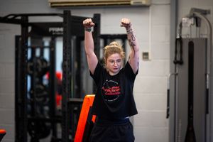 Fitness training session in a bright indoor gym space with orange equipment.